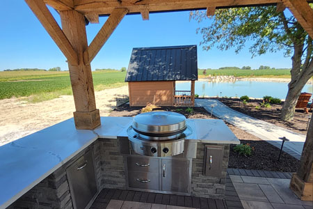 Outdoor kitchen with grill by a pond.
