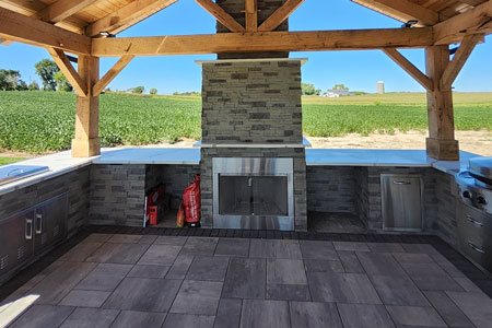 Outdoor kitchen with fireplace and countryside view.