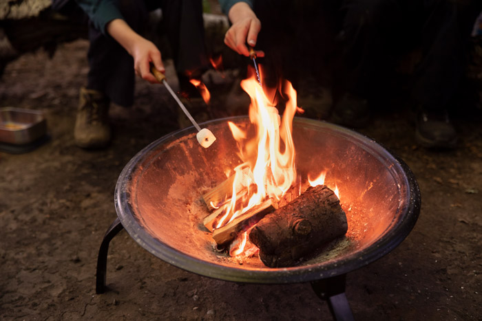 Roasting marshmallows over a campfire in fire pit.